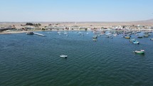 Aerial shot drone flies to the left at a distance from the boat marina in Paracas, Peru