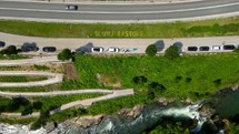 Aerial shot drone descends over highway, walking path, and city sign in grass in Rastoke, Slunj, Croatia