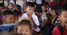 Close up of a classroom of Southeast Asian elementary students praying.