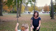 grandmother pushing her granddaughter on a swing 