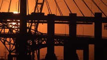 Telephoto lens silhouette of suspension bridge with sun in Long Beach California USA