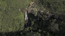 Drone orbits to the left from up high looking down at Véu das Noivas waterfall in Parque das Andorinhas