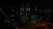 Aerial shot drone flies right and pans left around Basílica del Voto Nacional in Quito at night