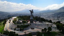 Aerial shot drone flies to left while keeping center the front of Panecillo, the virgin statue on the hill overlooking the city Quito