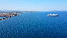 Aerial shot drone flying toward coast as cruise ship exits port in Chania, Crete, Greece