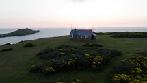 Coast Guard Hut Sitting On A Beautiful Grassy Hillside Over Looking The Open Ocean And Setting Sun