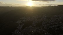 Drone descends from very high over Ouro Preto, Brazil at sunset down to the city center
