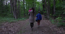 Mother and young kids walking to camp grounds in middle of woods - summer vacation