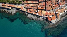 Aerial shot drone flies with camera down from north coast toward city center of Cefalu, Sicily, Italy