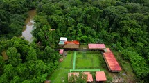 Aerial shot drone flies right in semicircle around lodge on brown river in middle of Amazon rainforest