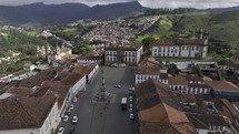 Drone flies up and away to the north from historic center of Ouro Preto, Brazil on partly cloudy day