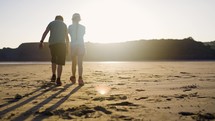 Young Boy And Girl Walking On The Beach Having Fun Together In The Warm Setting Sun