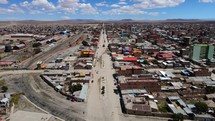 Aerial shot drone flies forward while descending on main street in town with dirt roads