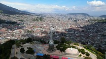 Aerial shot drone flies over the top of Panecillo, the virgin statue on the hill overlooking the city Quito