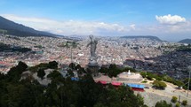 Aerial shot drone rises up behind Panecillo, the virgin statue on the hill overlooking the city Quito
