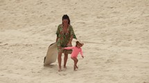Mother and young daughter walk sand board up sand dunes on hot summer day - unique activity - Brazil