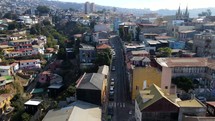 Aerial shot drone flies up street in popular tourist area on top of the hill in coastal city