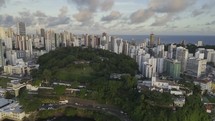 Drone flies from sea toward high rise buildings in Barra at sunset in Salvador, Bahia, Brazil