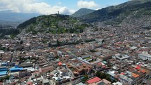 Aerial shot drone flies forward over downtown Quito toward virgin statue, Panecillo overlooking the city