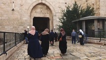 Muslim Women walking through ancient city wall Middle East