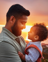 Father looking down at his kid during a golden sunset for Fathers Day.