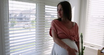 Pregnant woman looking out her bedroom window