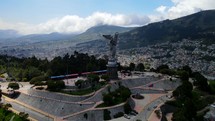 Aerial shot drone flies to left and behind Panecillo, the virgin statue on the hill overlooking the city Quito