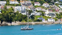 Sail boats crossing on a popular estuary holiday destination in summer vacation homes in view
