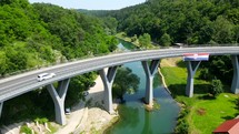 Aerial shot drone flies up and to right over highway with Croatia flag in Rastoke, Croatia