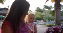 Grandmother holding young curious granddaugther in arms outdoors in tropical location