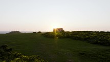 Setting Sun Over A Lone Coast Guard Hut Set On A Beautiful Grassy Ocean Hillside
