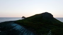 The Setting Sun Appears Over A Spectacular Coastal Island With Wild Sheep Grazing