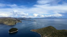 Aerial shot drone slowly descends over east side of Isla del Sol in Lake Titicaca with Copacabana in the distance