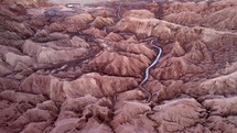 Aerial shot drone flies forward over river flowing through Death Valley in Atacama Desert at sunset