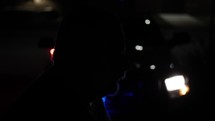 Silhouette of a criminal man being arrested in front of flashing police officer, cop car lights at night in slow motion.