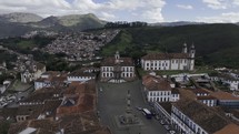 Drone flies backwards from Museu da Inconfidência in Praça Tiradentes in Ouro Preto, Brazil in the late afternoon