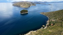 Aerial shot drone flies backward from southeast side of Isla del Sol in Lake Titicaca