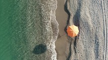 Orange umbrella near the calm waves of the sea at Summer