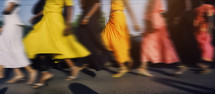 AI generated image. Defocused and motion blurred low section image of unrecognizable people wearing colorful dresses in the city