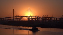 Silhouette of tugboat and suspension bridge with sun in Long Beach California USA