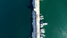 Aerial shot drone flies backwards with camera down over stone pier with boats docked in Palermo, Sicily, Italy