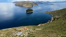 Aerial shot drone flies left while panning right over the southeast side of Isla del Sol in Lake Titicaca