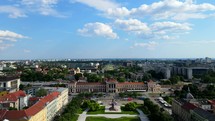 Aerial shot drone lowers from view of train station to in front of art pavillion in Zagreb, Croatia