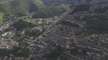 Drone facing west descends from high up onto Praça Tiradentes in historic center of Ouro Preto, Brazil
