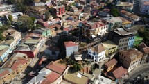 Aerial shot drone slowly orbits to left around backside of funicular on hill in coastal city