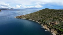 Aerial shot drone flies backwards and pans rights over Isla del Sol in Lake Titicaca