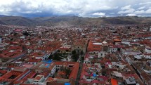 Aerial shot drone flies over silver mining town with red clay roofs toward main square and cathedral