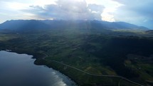 Aerial shot drone flies forward over Lake Huaypo into the sun creating a prism effect on the clouds