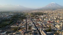 Aerial shot drone flies over Arequipa toward Misti Volcano and Chachani volcano at dusk