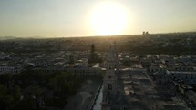 Aerial shot drone descends behind steeples of Basilica Cathedral of Arequipa at dusk with the sun behind the towers